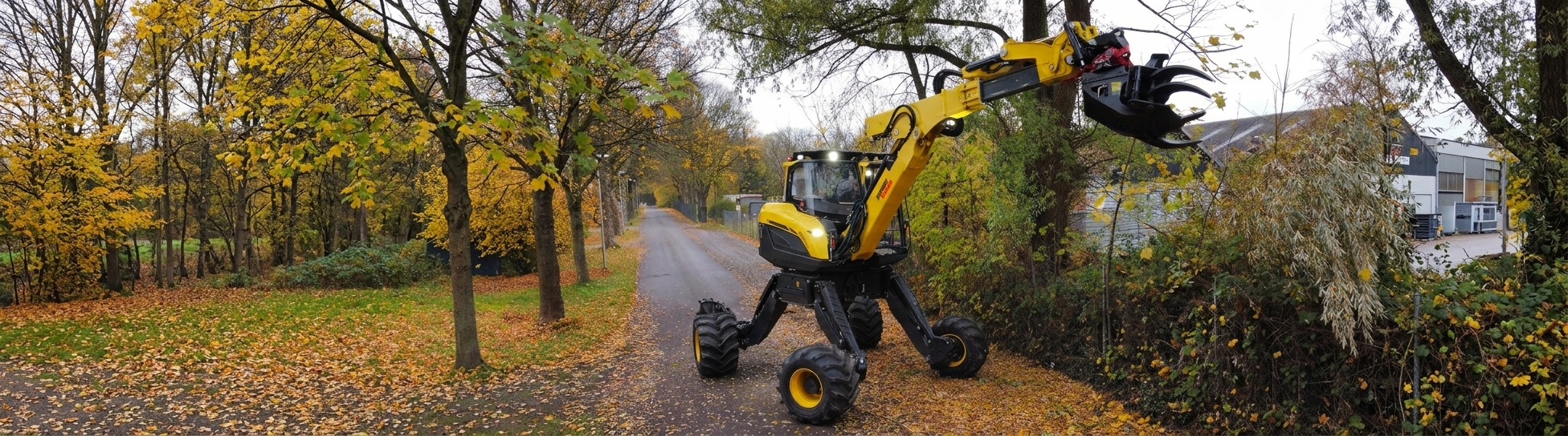 Gelber Menzi Muck M445x Schreitbagger mit Holzgreifer auf einer laubbedeckten Straße im Herbst.